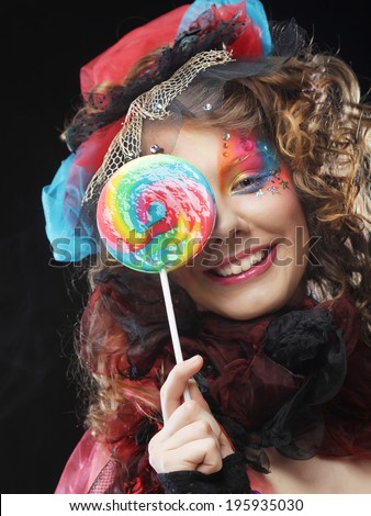 Girl with with creative make-up holds lollipop. Doll style. Studio shot.