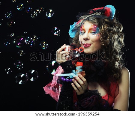 Fashion model with creative make-up blowing soap bubbles. Doll style.
