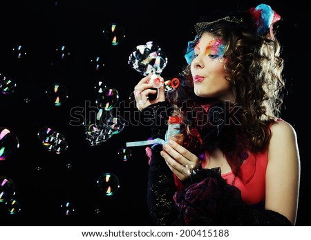 Fashion model with creative make-up blowing soap bubbles. Doll style.