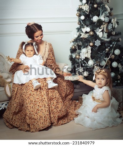 Young mother and her two little daughters near Christmas tree in living room. Retro style.
