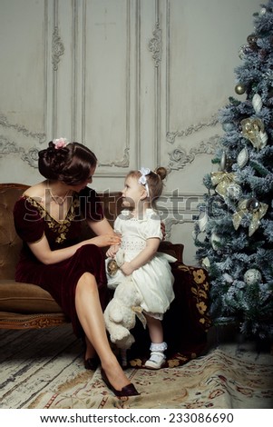 Child with mother receiving near Christmas tree. Retro style.