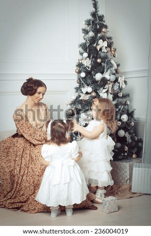 Young mother and her two little daughters near Christmas tree in living room. Retro style.
