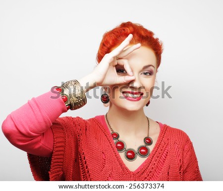 Pretty young woman looking for something with wide open eyes and imaginary binocular.