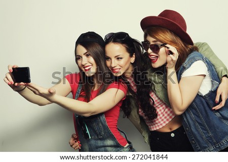 Three stylish sexy hipster girls best friends taking selfie with mobile phone