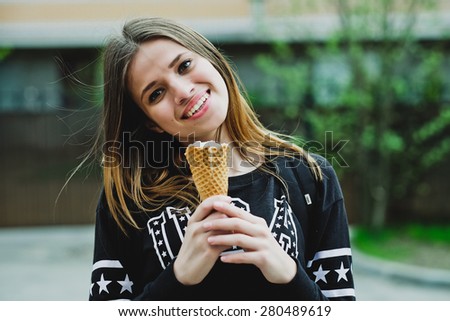 young woman eating ice-cream sunny day outdoors, near big house