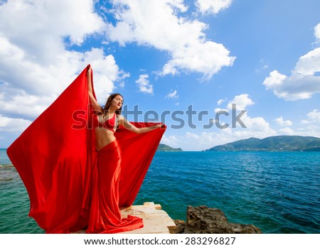 Young woman with red skirt and  fabric like a wings. Vogue style.