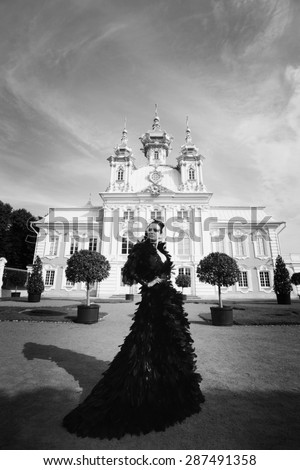 Beautiful woman in black dress posing next to the palace. Dark Queen.