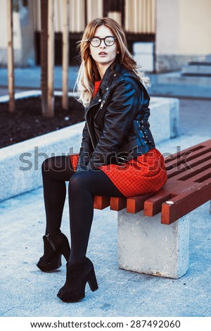 Girl Sitting on Bench. Street Fashion. Urban Lifestyle. Young Beautiful Woman Walking Outdoor.Image toned.