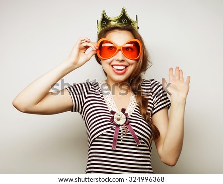 Party image. Playful young woman with big party glasses and crown. Ready for good time.