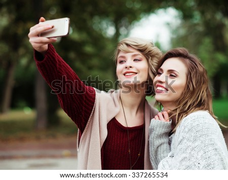 life style, happiness, emotional and people concept: Friends making selfie. Two beautiful young women making selfie in autumn park.