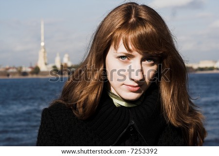 Portrait of a young redhead woman standing by a river  in St. Petersburg, Russia