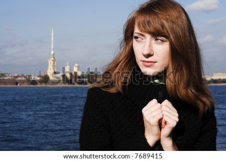 Portrait of a young redhead woman standing by a river  in St. Petersburg, Russia