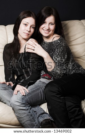 Two beautiful models, dressed in casual wear sitteng on sofa