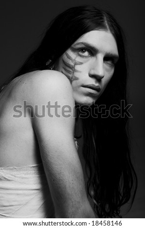 Black-and-white studio portrait of a young man with paint on his face and bandage on his body