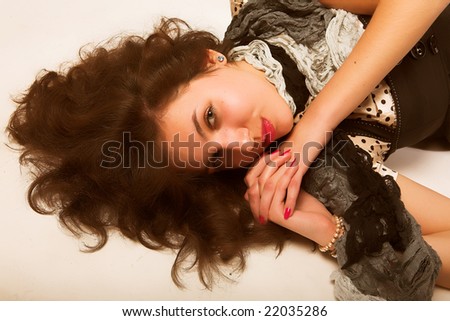 Young woman with long brown  curly hair and green  eyes laying on floor.