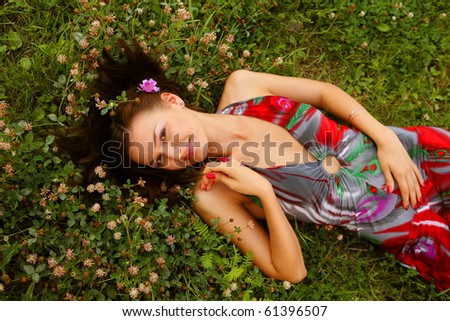 Cute young redhead female lying on grass field at the park