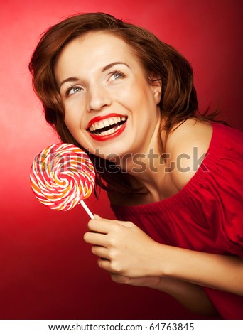 Portrait of young woman with lollipop on red background