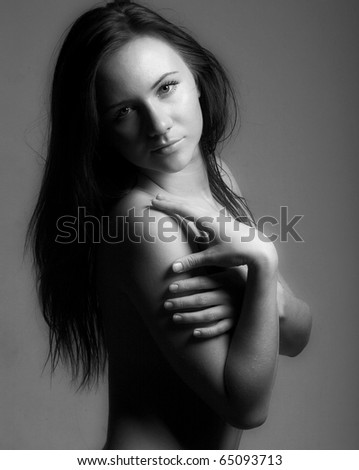 Studio portrait of a topless modest girl in semidarkness