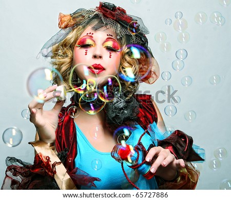fashion model with creative make-up blowing soap bubbles. Doll style.