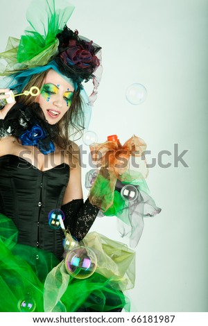 fashion model with creative make-up blowing soap bubbles. Doll style.