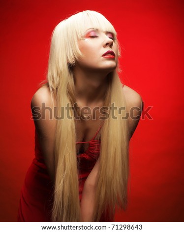 Perfect blond model in red dress over red background. Fantasy make-up.