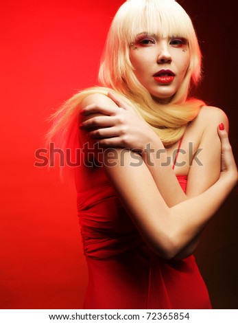Perfect blond model in red dress over red background. Fantasy make-up.