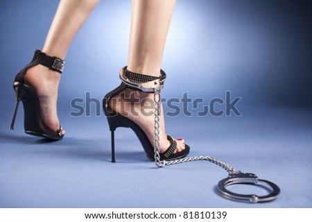 High heels and ankle cuffs A sexy woman\'s ankles, wearing very high-heeled black sandals, with crystals applied and a ankle cuff around the right leg.