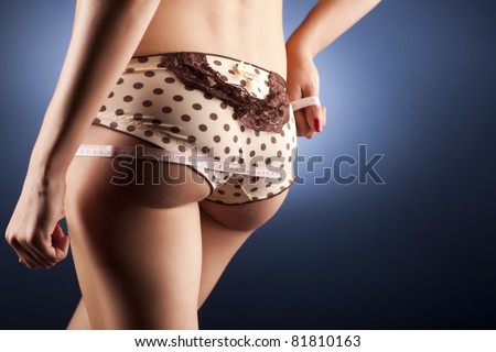 Young woman with a sexy body measuring herself. Wearing beige with brown dots and lace panties, has a very smooth skin and beautiful body.