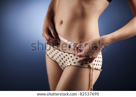 Young woman in bikinis with a sexy body measuring her waist. Wearing beige with brown dots and lace panties, has a very smooth skin and beautiful body