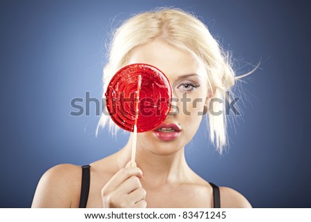 Beautiful blonde model hides her face behind a big round red lollipop.