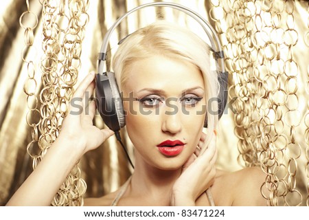 Portrait of a sexy blonde, with red lips and headphones on a gold background.