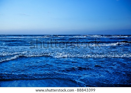 Beautiful sea shore, waves breaking fast. Cold blue tones.