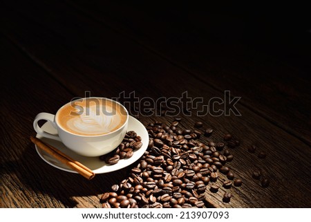 Cup of cafe latte and coffee beans on old wooden background