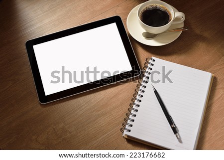 Tablet computer with notepad and coffee cup on wooden background