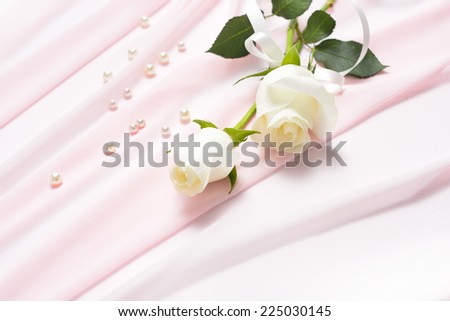 White rose flowers tied with ribbon on pink cloth with pearls