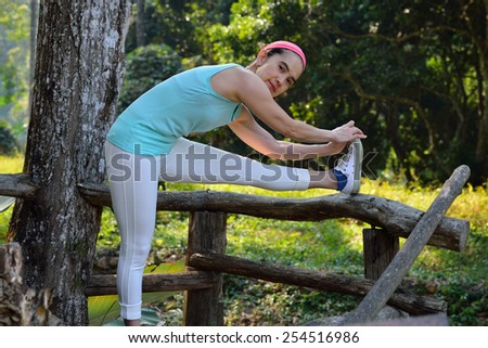 Middle aged woman bending over to do stretching in the park