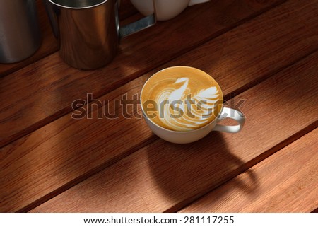 Cup of cafe latte on wooden table, bird shape