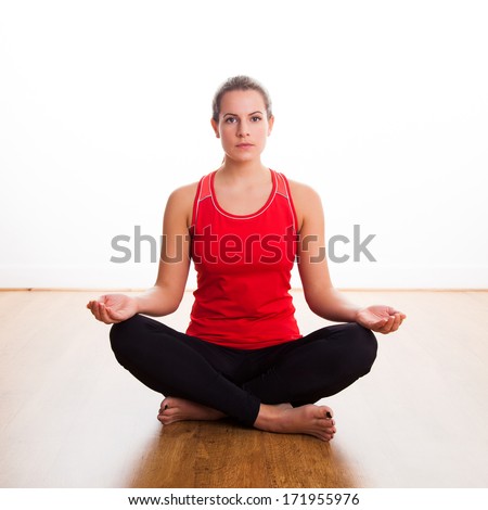 Woman sitting cross legged doing a yoga pose in the studio, with open eyes