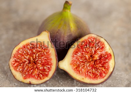 Two fresh figs, one whole and one sliced in half.