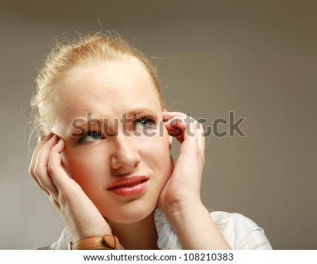 A young woman with a headache holding head, isolated on grey background