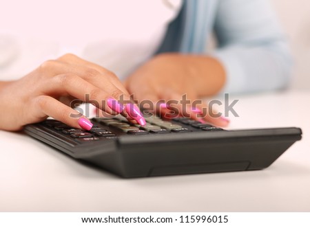 Businesswoman doing some paperwork at her desk using a calculator