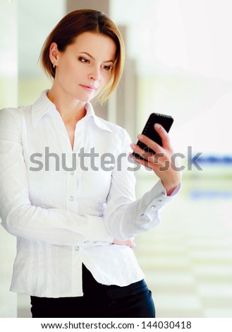 Portrait of young businesswoman talking on mobile phone on office hallway.