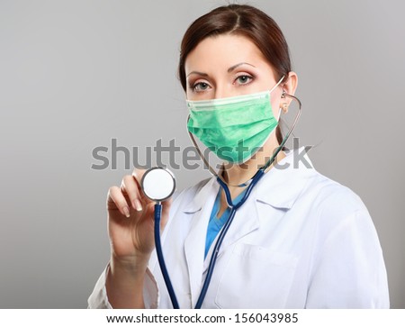 Female doctor using stethoscope isolated on grey background
