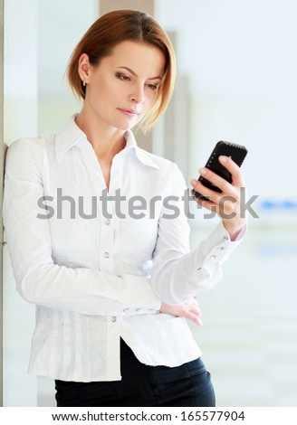 Portrait of young businesswoman talking on mobile phone on office hallway