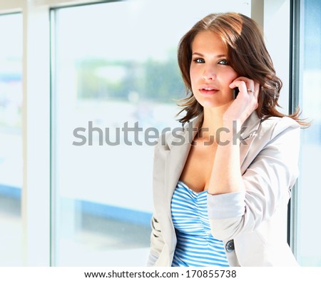 Portrait of young businesswoman talking on mobile phone on office hallway