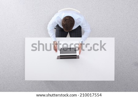 Young man  working on laptop, sitting  the desk in office