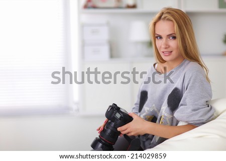 Woman sitting on a sofa in her house with camera at home