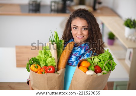 Young woman holding grocery shopping bag with vegetables Standing in the kitchen.