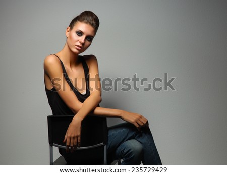 Beautiful woman  sitting  a chair, isolated on gray background