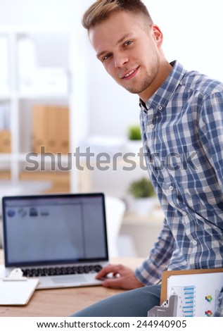 Smiling businessman with red folder sitting in the office